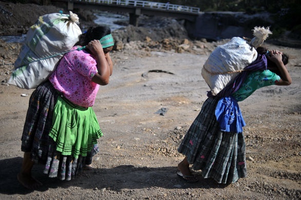 11 February 2009: Chinautla, Guatemala: A woman and her daughter carry sacks of mud