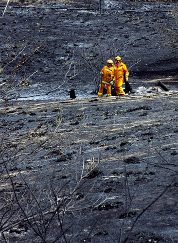 Two firefighters survey the scorched landscape following the devastating bush fires in Bendigo, Australia. Photograph: Scott Barbour / Getty Images