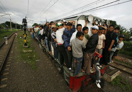 24 hours in pictures: Commuters hang on to the outside of a train in Indonesia