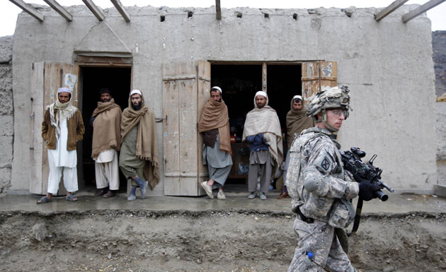 24 hours in pictures: A U.S. soldier walks in front a group of Afghan men 