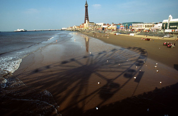Big wheels : A ferris wheel on a pier casts a shadow on Blackpool Beach.