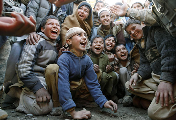 17 February 2009: Damman, Afghanistan: Boys play a game of marbles with a US officer