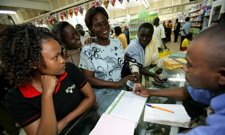 Customers use a mobile phone to transfer money in Bungoma, Kenya