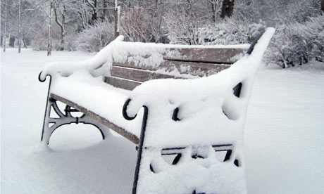 A park bench covered in snow