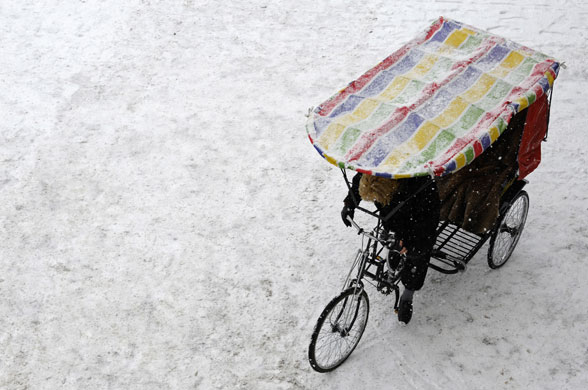 20 February 2009: Berlin, Germany: A rickshaw driver makes her way through the snow
