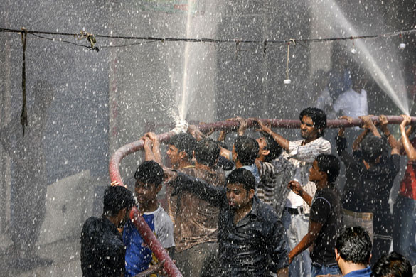 20 February 2009: Dhaka, Bangladesh: People help as firefighters try to extinguish a fire