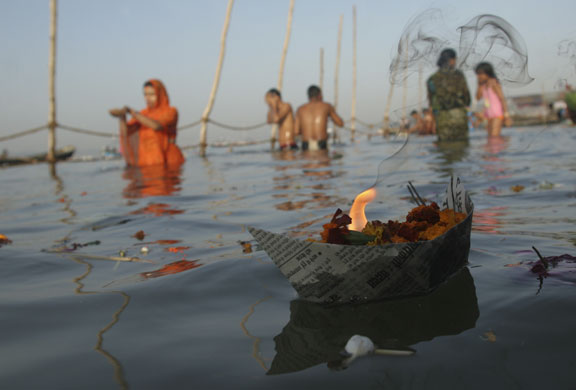 23 February 2009: India: A lamp floats in the water as Hindu devotees offer prayers