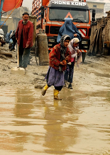23 February 2009: Kabul, Afghanistan: A woman and her children walk along a muddy road