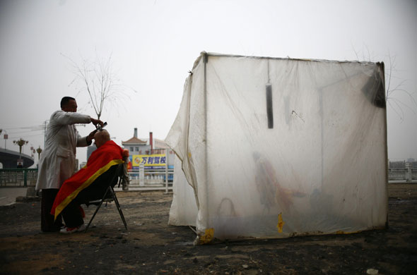 26 February 2009: Changchun, China: A street barber cuts a senior citizen's hair
