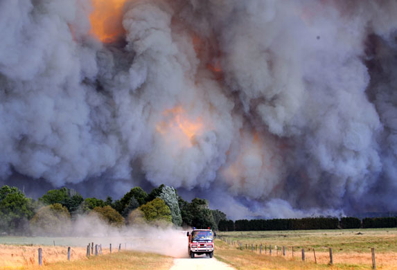 A fire engine drives away from flames burning near Labertouche, east of Melbourne. Photograph: A Coppel / Newspix / Rex Features