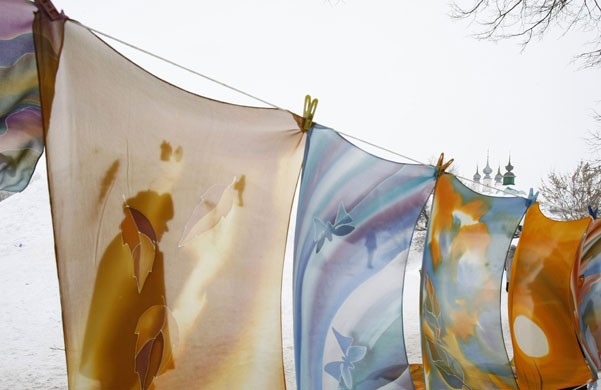 Suzdal, Russia: A man is seen through scarves displayed for sale.