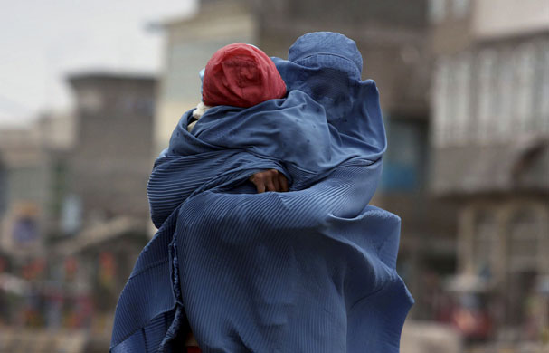 Herat, Afghanistan: An Afghan woman holds her child on a windy day.