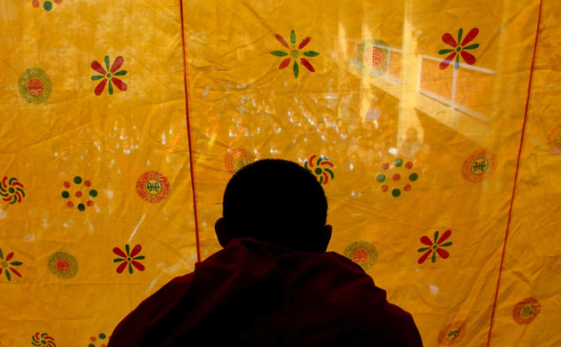 Kathmandu Uprising day: A monk looks through a curtain during Uprising day in Kathmandu, Nepal. 