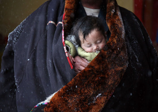 24 hours in pictures: A Tibetan pilgrim carries his child  as he prays in a temple Xining, China 