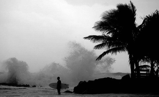 24sport:  A surfer prepares to paddle out as a wave explodes over Snapper Rocks