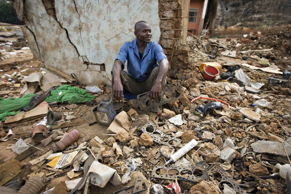 24 hours : Local businessman sits amongst his destroyed stall in Cameroon