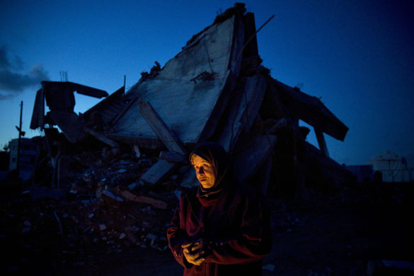 2 March 2009: Jebaliya, Gaza Strip: A woman keeps herself warm next to a destroyed house