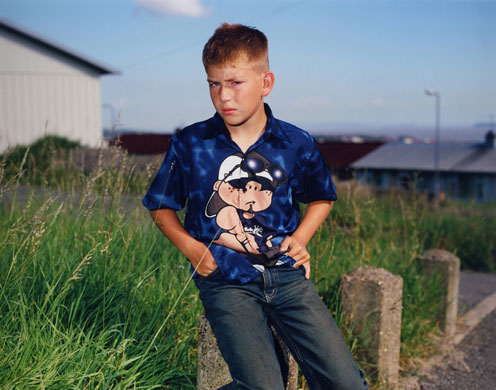 Young Carers: A boy sits outside looking awkward.