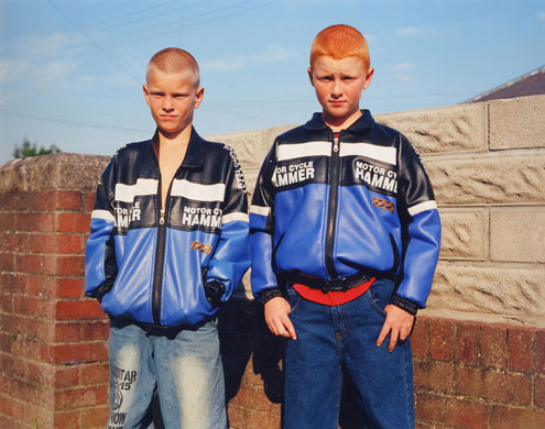 Young Carers: Two similar boys stand by a wall defiantly.