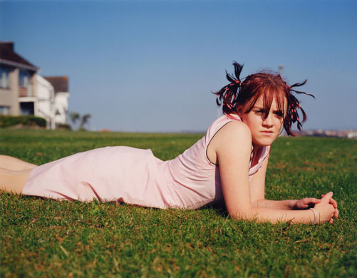 Young Carers: A girl lays casually on her stomach on the grass
