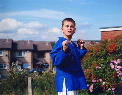 Young Carers: A boy hesitantly shows a karate move outside.