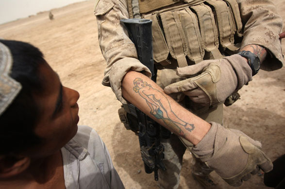 Kirta, Afghanistan: A US Marine shows off a tattoo to a local boy while on 