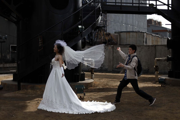 26 March 2009: Beijing: A photographer's assistant prepares a bride for a photoshoot