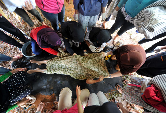 Burst dam in Indonesia: Volounteers carry a dead body at a make-shift morgue in Tangerang