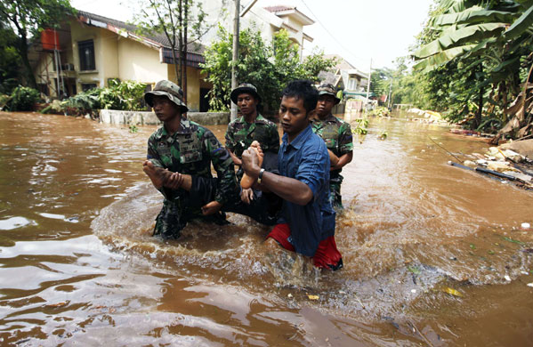 Burst dam in Indonesia: A survivor is carried through the floodwater