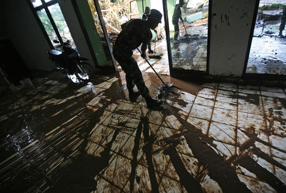 Dam bursts in Indonesia: soldier cleans up mud from a building after a dam burst Jakarta, Indonesia.
