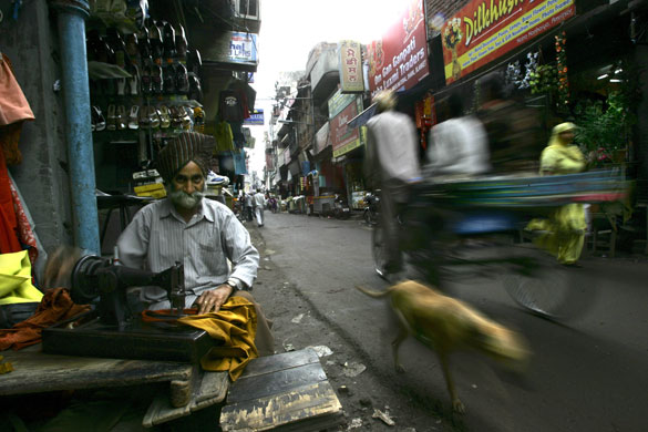 27 March 2009: Amritsar, India: An elderly roadside tailor tends to his business