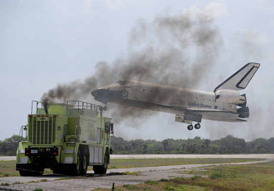24 hours in pictures: Florida, USA: Space shuttle Discovery lands as a fire engine waits.