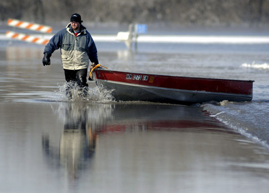 Red River floods: Jared Bakko hauls a boat down a flooded road after delivering supplies.