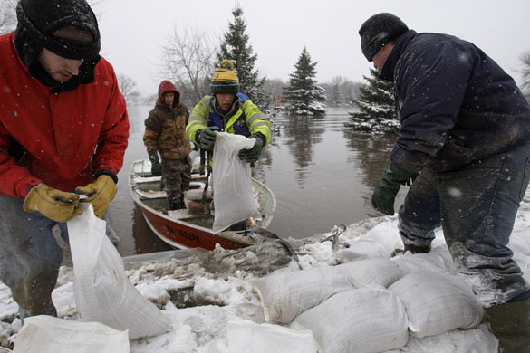 Red River floods: Local men struggle in the snow to unload a boat full of sandbags.