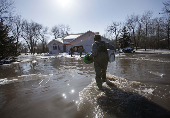 Red River floods: Minnesota National Guard wades through water with supplies to home owners 
