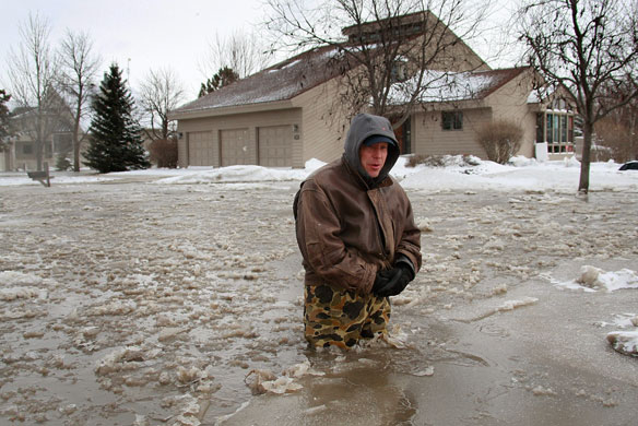 Red River floods:  John Iverson wades through icy water after leaving his home in Oxbow.