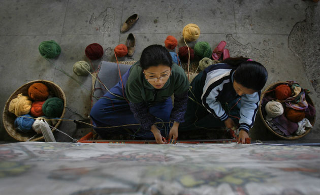 3 March 2009: Katmandu, Nepal: Tibetan women weave a carpet at the Tibetan refugee camp