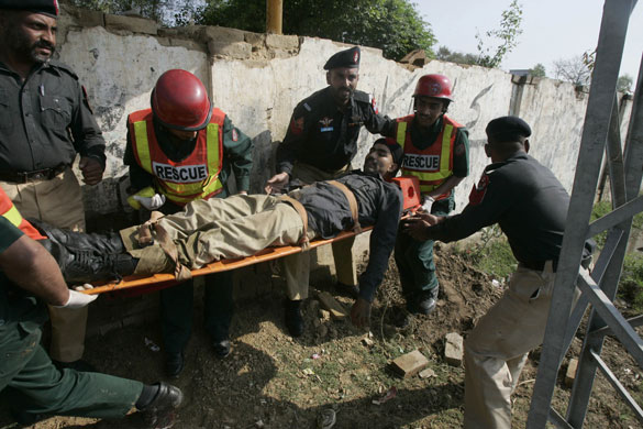 Siege in Lahore: Pakistani police officers carry their colleague injured in a shootout.