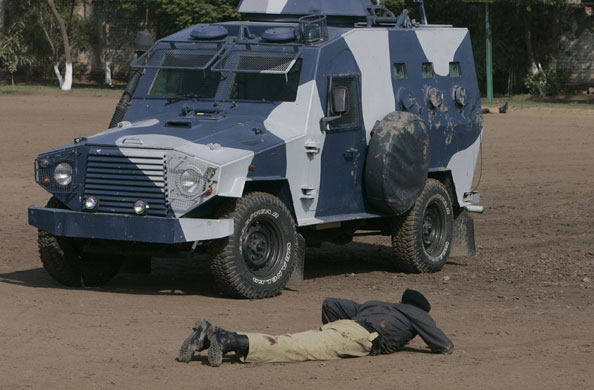 Siege in Lahore: An injured Pakistani police officer crawls towards an armored vehicle.