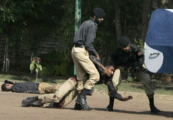 Siege in Lahore: Pakistani police officers carry their injured colleague.