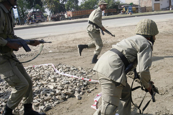 Siege in Lahore: Paramilitary troops charge towards the site of a shooting.
