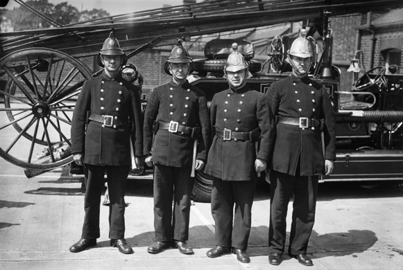 Firefighter uniforms: 1934: London firemen wearing the new and old versions of their headgear