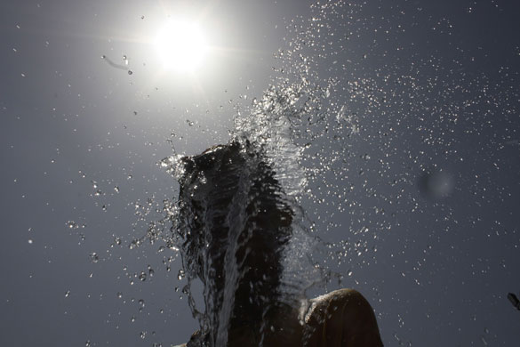 24 hours in pictures: A boy takes a bath on a hot day  in the western Indian city of Ahmedabad