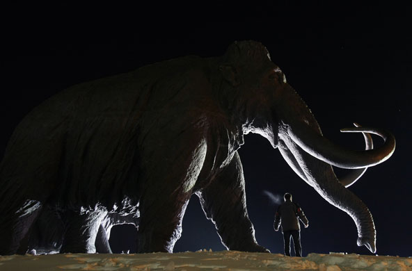 24 hours : A man stands under a bronze sculpture of a mammoth in Siberia 