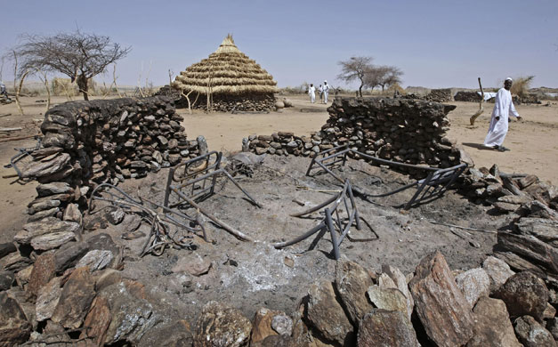 Darfur atrocities: A man walks past a destroyed homestead in the village of Kafod, Darfur.