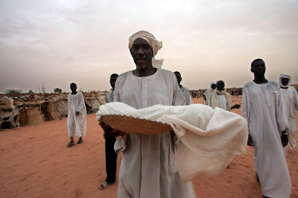 Darfur atrocities: A father carries his son's body at a refugee camp in Darfur