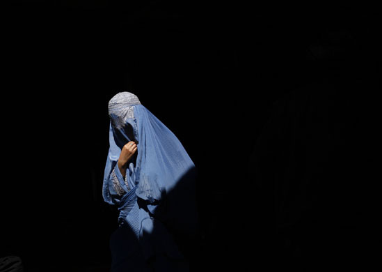 24 hours in pictures : A burqa-clad Afghan woman walks in an old bazaar in Kabul