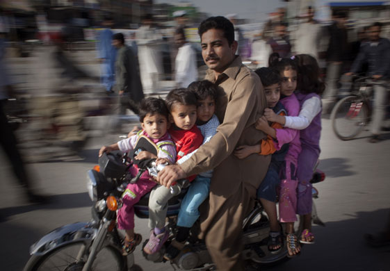 24 hours in pictures: Aman drives a motorcycle carrying children in Rawalpindi, Pakistan