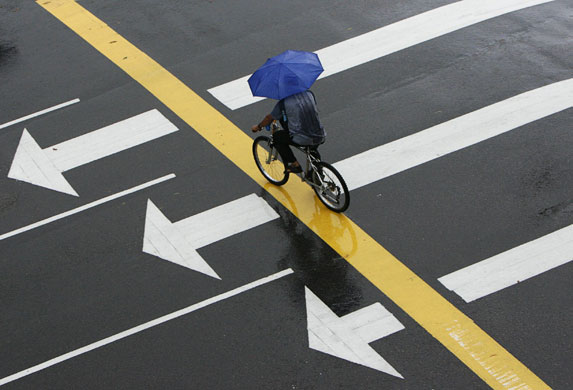 24 hours in pictures: A man carries an umbrella while riding a bicycle in the rain in Singapore