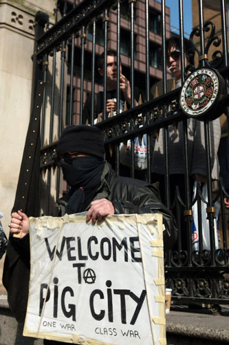 G20 protests and security: A man holds up a banner reading Welcome to Pig City at a G20 protest.